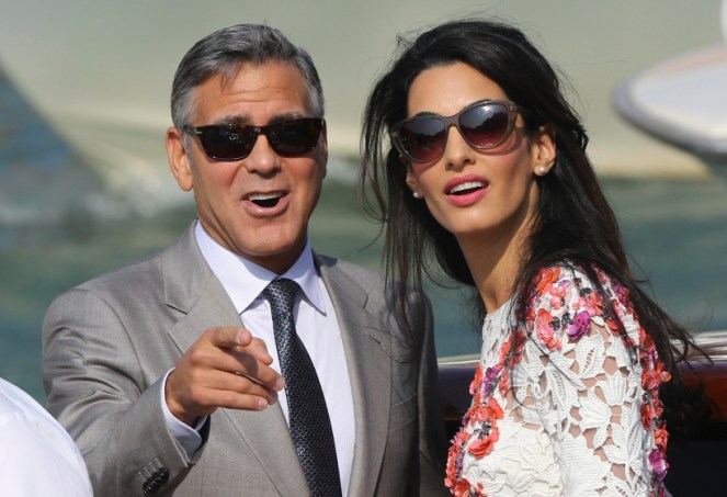 U.S. actor George Clooney and his wife Amal Alamuddin stand on a water taxi on the Grand Canal in Venice