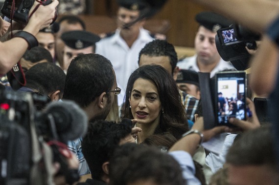Amal Clooney (C), the human rights lawyer representing Canadian Al-Jazeera journalist Mohamed Fahmy (unseen), talks to the press during the trial of Fahmy and Egyptian Baher Mohamed, both accused of supporting the blacklisted Muslim Brotherhood in their coverage for the Qatari-owned broadcaster, on August 29, 2015, in the capital Cairo. The court sentenced Fahmy and Mohamed, along with Australian journalist Peter Greste who was tried in absentia after his deportation early this year, to three years in prison in a shock ruling following global demands for their acquittal. AFP PHOTO / KHALED DESOUKI (Photo credit should read KHALED DESOUKI/AFP/Getty Images)